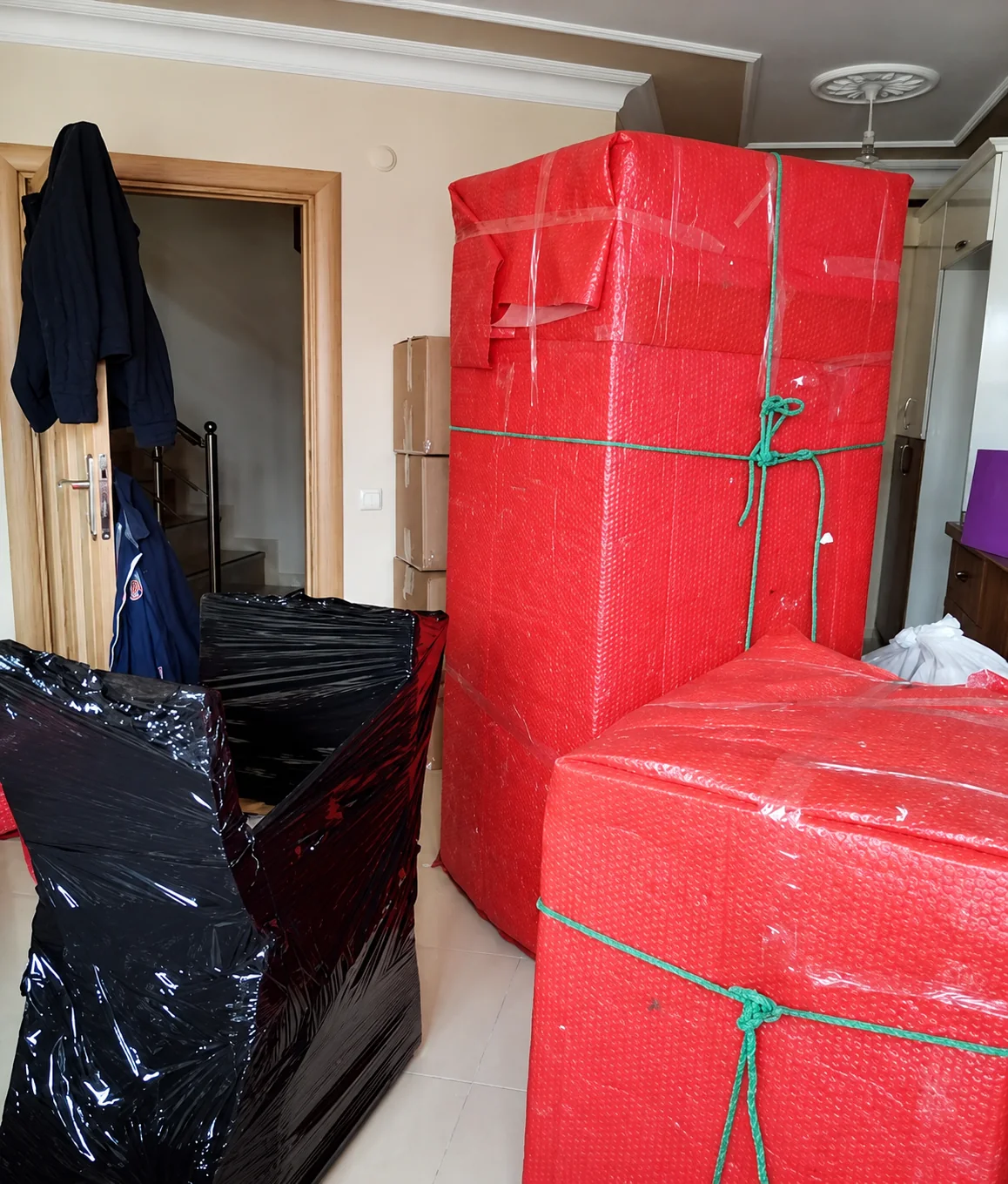 Kırmızı koruyucu ambalaj ve bağlarla paketlenmiş mobilyalar